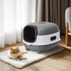 A cat is lying on a rug next to a closed litter box. Anteprima dell’immagine prodotto