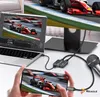 A setup showing a laptop, a monitor displaying a racing car, a capture card, and a microphone, with a smartphone in hand also displaying the racing car. Náhled obrázku produktu