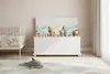 A child's bedroom with a white toy chest filled with stuffed animals and pillows, a crib, and a rug with cloud patterns. Anteprima dell’immagine prodotto
