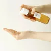 A hand is dispensing a liquid from a bottle into another hand. Anteprima dell’immagine prodotto