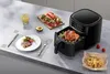 A kitchen counter with an air fryer, a plate of food, a drink, and some ingredients. Produktbild-Vorschau