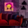A pop art style neon sign of a woman wearing sunglasses is displayed on a concrete wall above a red sofa. Voir les images du produit