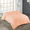 A peach-colored duvet is laid out on a bed in a room with a large window and a nightstand. Produktbild-Vorschau