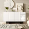 A modern white sideboard with black accents is displayed in a living room setting, adorned with decorative items and artwork. Anteprima dell’immagine prodotto