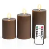 Three brown LED candles of varying heights are arranged on a white surface, with a remote control placed in front of the largest candle. Anteprima dell’immagine prodotto