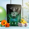 A bag of Verde Mate Green Fitness yerba mate is displayed with fitness equipment and flowers. Produktbild-Vorschau