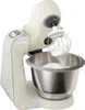 A cream-colored Bosch stand mixer with a whisk attachment is shown in a studio setting against a white background. The mixer is in the process of whipping egg whites, which are visible on the whisk and in the stainless steel bowl. Produktbild-Vorschau