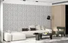 A modern living room with a sectional sofa, coffee table, and accent chair, featuring a textured 3D wall paneling. Podgląd zdjęcia produktu