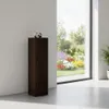 A dark wood pedestal with a silver sculpture on top, placed indoors next to a large window overlooking a garden. Produktbild-Vorschau