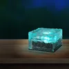 A single illuminated ice cube-shaped solar light sits on a wooden surface against a dark, blurred background. Produktbild-Vorschau