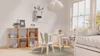 A bright and airy children's room with a wooden cube shelf, a small table and chairs, and a bed. Produktbild-Vorschau