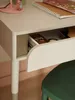 A close-up view of a desk with an open drawer, revealing some stationery items. A green chair is partially visible in the foreground. Produktbild-Vorschau
