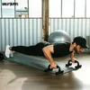 A man is doing push-ups on a yoga mat with push-up bars in a gym-like setting. Produktbild-Vorschau