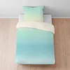 A duvet cover and pillow set with a gradient color design is laid out on a bed. Produktbild-Vorschau