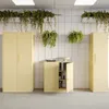 A studio shot of three beige filing cabinets against a tiled white wall with hanging plants. Voir les images du produit