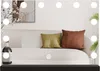 A vanity mirror with lights is placed on a shelf in front of a couch with pillows and a plant. Produktbild-Vorschau