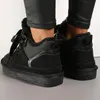 A person wearing black pants and black fur-lined sneakers. Anteprima dell’immagine prodotto
