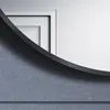 A close-up view of a round black mirror frame against a textured gray wall. Náhľad obrázku produktu