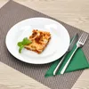 A slice of lasagna on a white plate, garnished with a basil leaf, placed on a placemat on a wooden table. Cutlery and a green napkin are to the side. Anteprima dell’immagine prodotto