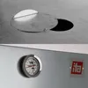 A close-up view of a metal smoker with a thermometer and a logo. Produktbild-Vorschau
