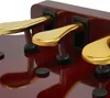 A close-up view of three gold piano pedals on a dark red wooden surface. Náhled obrázku produktu