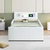 A white bed with a headboard featuring storage compartments and a night light, set in a child's bedroom with decorative wall panels. Produktbild-Vorschau