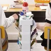 Two students are at a desk with a mobile shelving unit between them. Produktbild-Vorschau