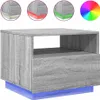 A grey wooden bedside table with blue LED lighting underneath, shown against a white background. Three circular insets show close-ups of the table's corners with different colored LED lights (green, red, and white). A color wheel is also shown. Produktbild-Vorschau