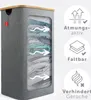 A grey fabric laundry basket with a wooden lid, showing clothes inside through a mesh window. Icons and text on the right describe features. Podgląd zdjęcia produktu
