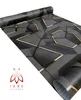 A roll of wallpaper with a geometric pattern and gold accents, displayed on a white background with a logo in the lower left corner. Anteprima dell’immagine prodotto