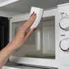 A hand is cleaning the inside of a microwave with a white sponge. Produktbild-Vorschau