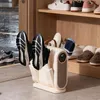 A shoe dryer with shoes on it, placed in a hallway or entryway with other shoes on shelves. Produktbild-Vorschau