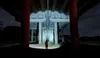 A person stands under a bridge at night, holding a flashlight. Produktbild-Vorschau