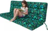 A young girl is sitting on a large, patterned cushion and reading a book. Voir les images du produit