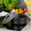 A black cast iron pot with its lid is placed on a black induction stove. In the background, there are fresh vegetables and a bottle of oil. Voir les images du produit