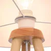 A close-up view of the top part of a tripod floor lamp, showing the wooden base, the light socket with a bulb, and the fabric lampshade. Podgląd zdjęcia produktu