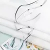 A close-up of folded white fabric with a black embroidered pattern. Produktbild-Vorschau