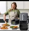 A woman is preparing food in a kitchen, with an air fryer and accessories on the counter. Produktbild-Vorschau