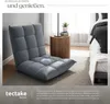 A gray floor chair is placed in a bedroom setting next to a bedside table and a bed. Náhled obrázku produktu