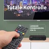 A hand holding a remote control in front of a TV screen displaying a city skyline and text, with a set-top box on a shelf below. Produktbild-Vorschau