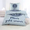 A neatly made bed with a nautical-themed duvet cover and pillowcase, set against a neutral background with a dresser and candles. Produktbild-Vorschau