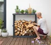 A man is arranging firewood in a rack next to a house. Podgląd zdjęcia produktu