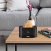 A black aroma diffuser with a flame effect sits on a wooden coffee table, next to a vase with pink flowers and a book. Voir les images du produit