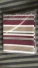 A folded awning fabric in plastic packaging, lying on a striped surface. Produktbild-Vorschau