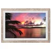 A framed picture of a tropical sunset over the ocean with a palm tree in the foreground. Produktbild-Vorschau