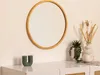 A round wooden mirror hangs on a wall above a white dresser. Decorative items like a candle and plants are placed on the dresser. Voir les images du produit