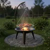 A BBQ grill with food cooking over a fire in a backyard setting at dusk. Podgląd zdjęcia produktu