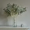 LED-lit olive branches in a glass vase on a shelf, next to a candle. Produktbild-Vorschau