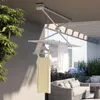 A retractable clothes drying rack mounted on a ceiling on a balcony with furniture and plants. Náhľad obrázku produktu