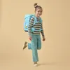 A young girl wearing a backpack poses with one leg raised. Náhľad obrázku produktu